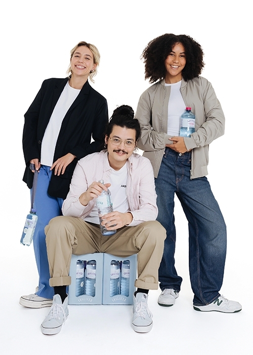 2 Frauen und ein Mann lächeln in die Kamera und halten Vöslauer Mineralwasserflaschen.