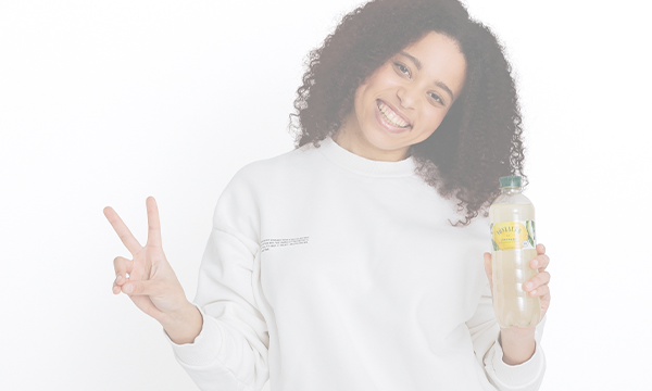 Lächelnde Frau zeigt Peace-Zeichen mit Vöslauer-Flasche – Gutscheine und Rabattaktionen