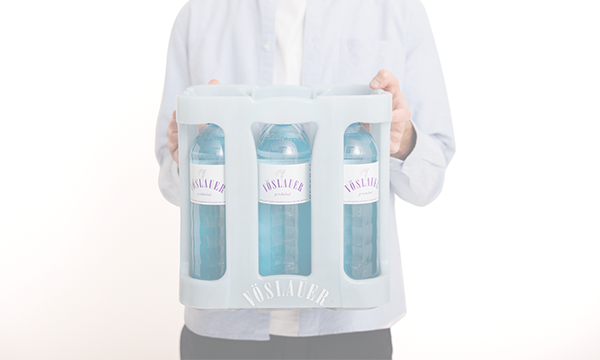 Mann hält eine Kiste mit Vöslauer 1l Glas-Mehrwegflaschen – Bestellungen im Design-Shop