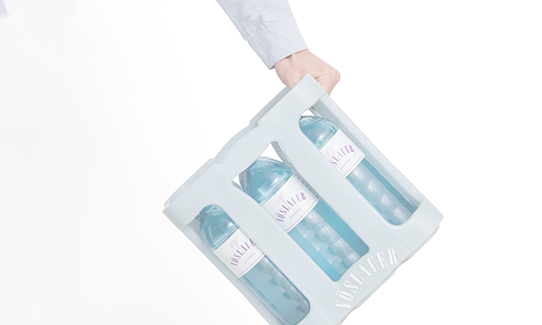 Person hält Kiste mit Vöslauer 1l PET-Mehrwegflaschen in der Hand – Versand & Lieferung Optionen